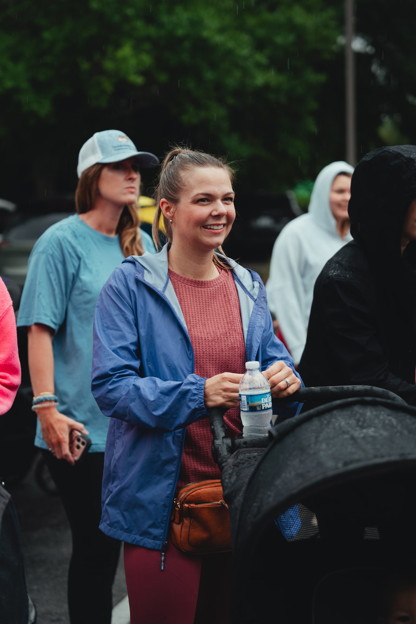 A mom in a blue jacket smiling with her stroller at Babes & Barbells